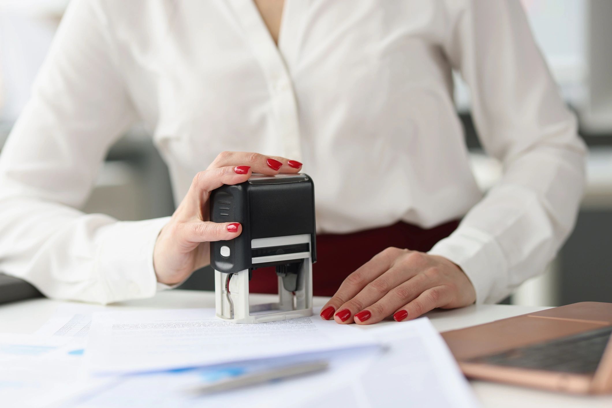 Person stamping documents with a red-handled stamp.