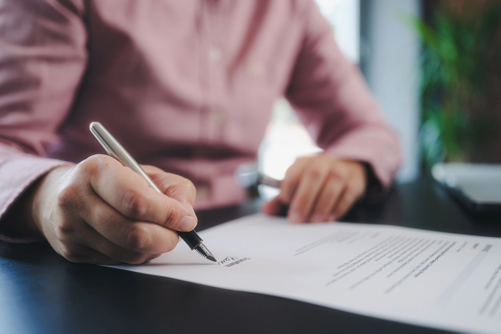 Person signing a document with a pen.