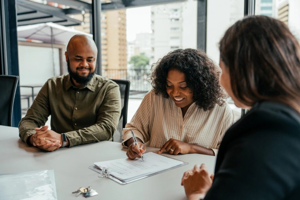 Three people discussing documents in a meeting room with city views.