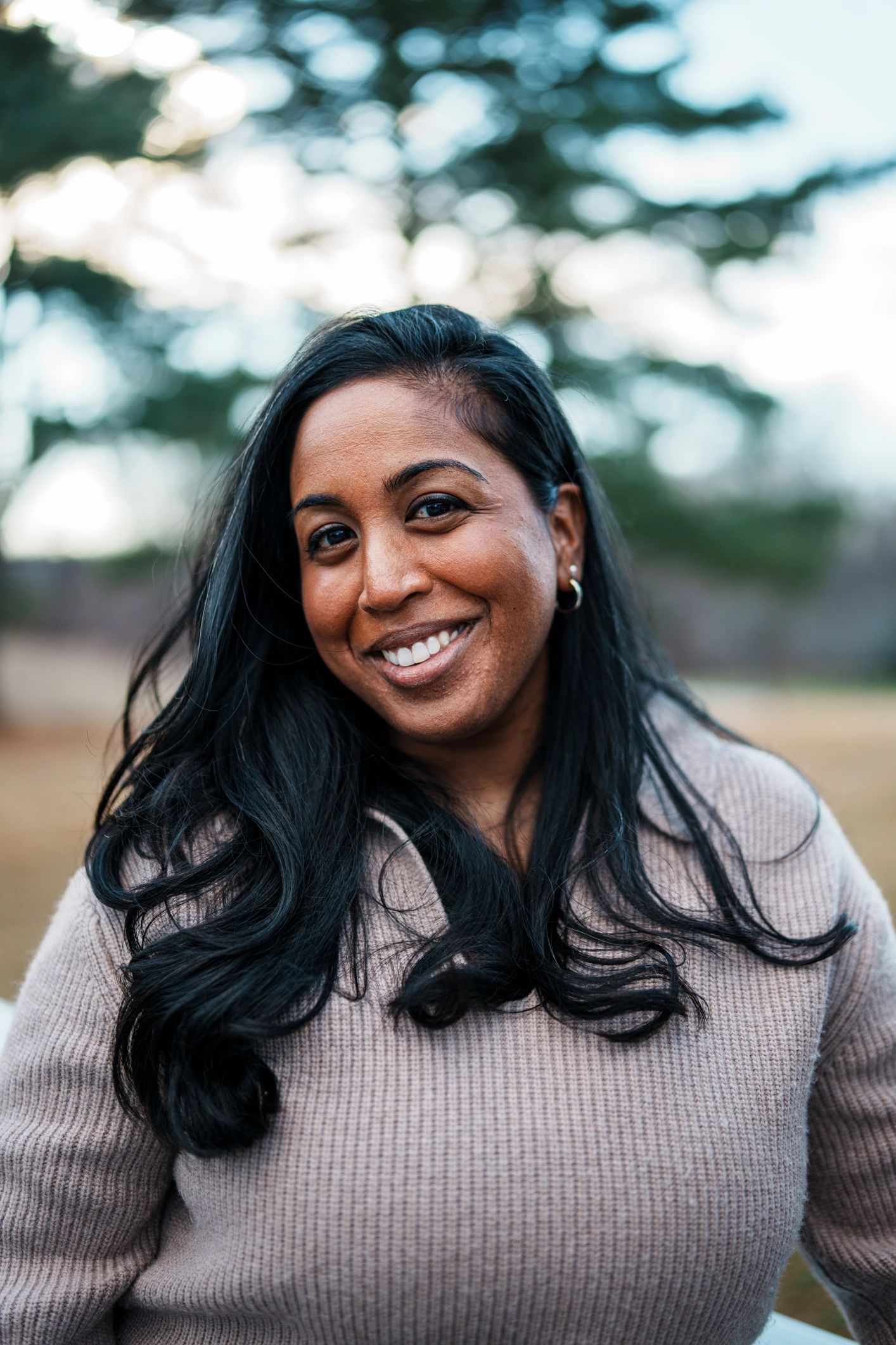 Smiling woman with long dark hair outdoors.