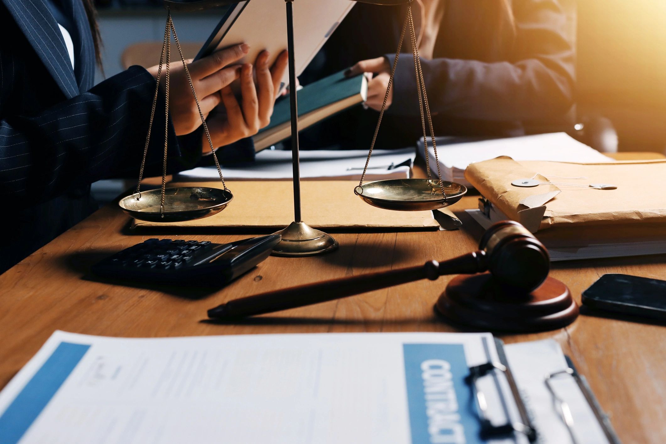 Legal consultation with scales of justice and gavel on desk.